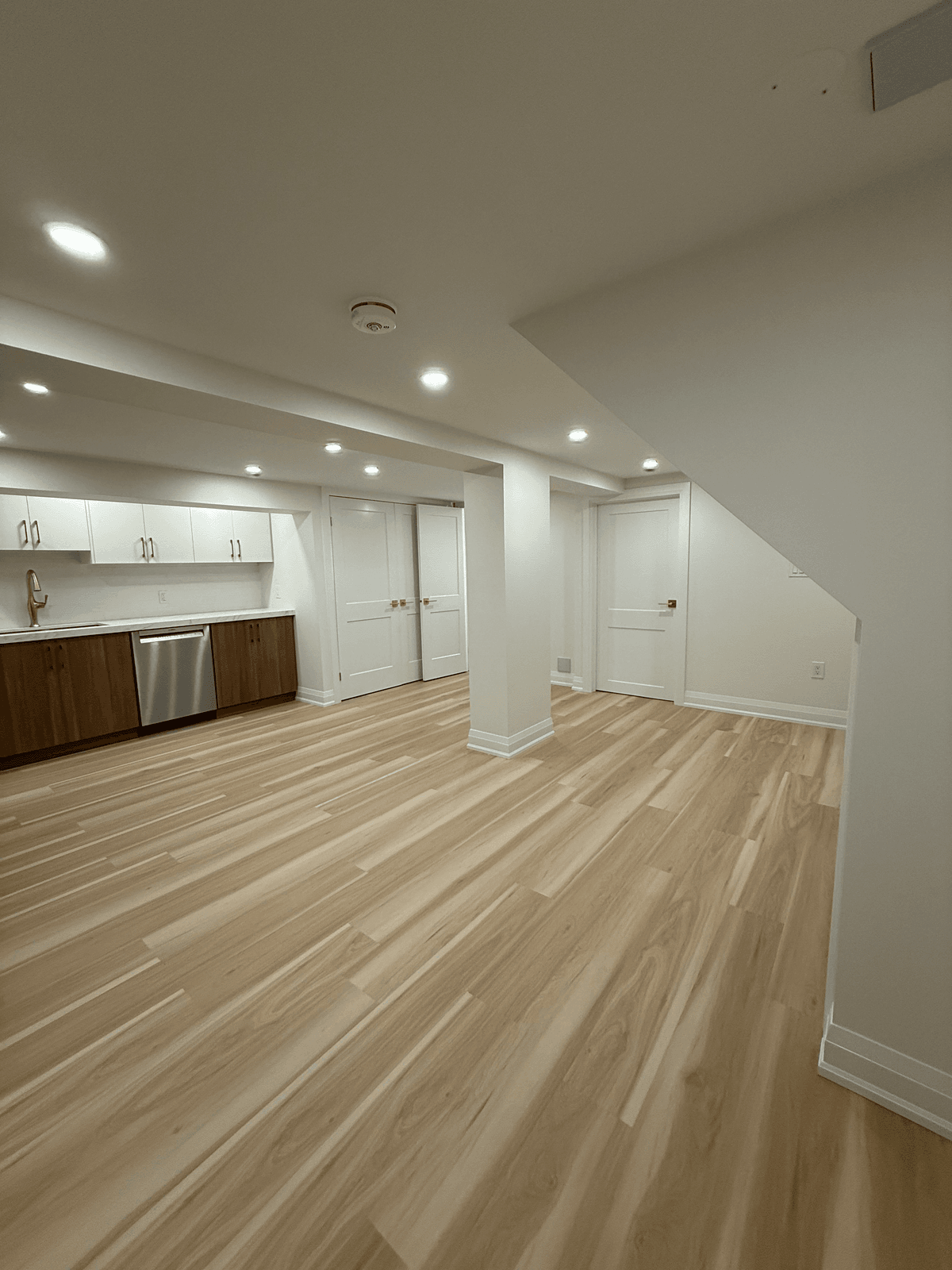 Finished bright basement with light wood floors and a kitchenette