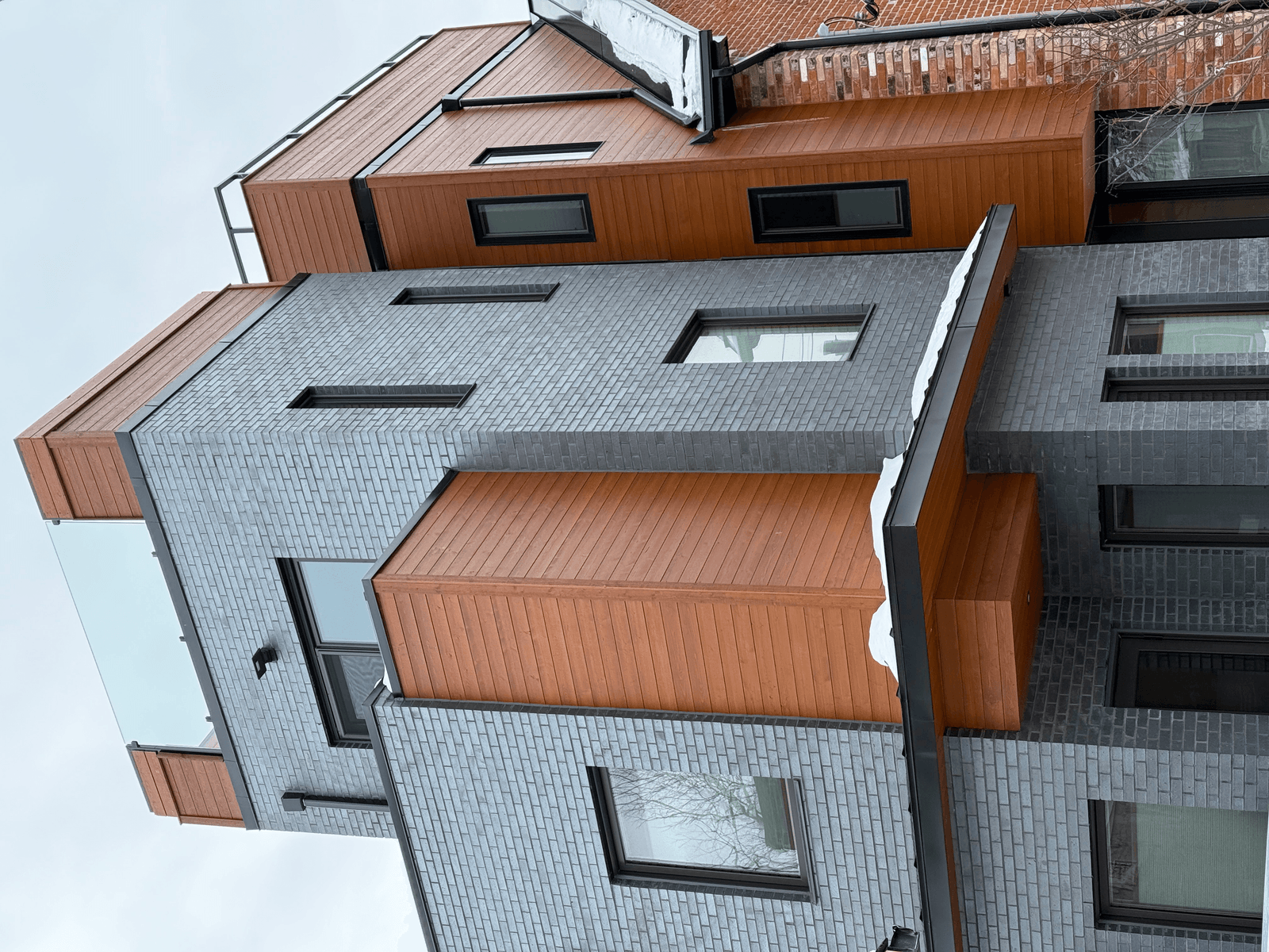 Modern custom home exterior in grey brick and warm wood cladding
